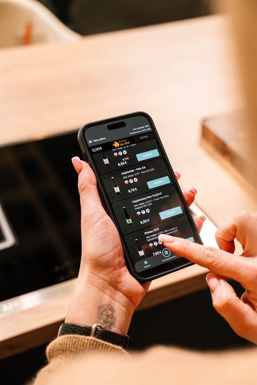 Cliente che sfoglia l'app della spesa sullo smartphone in cucina